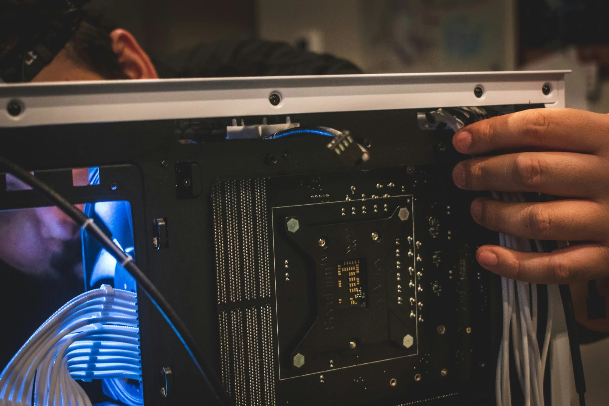 Hands fitting a motherboard into a PC case, cables already routed