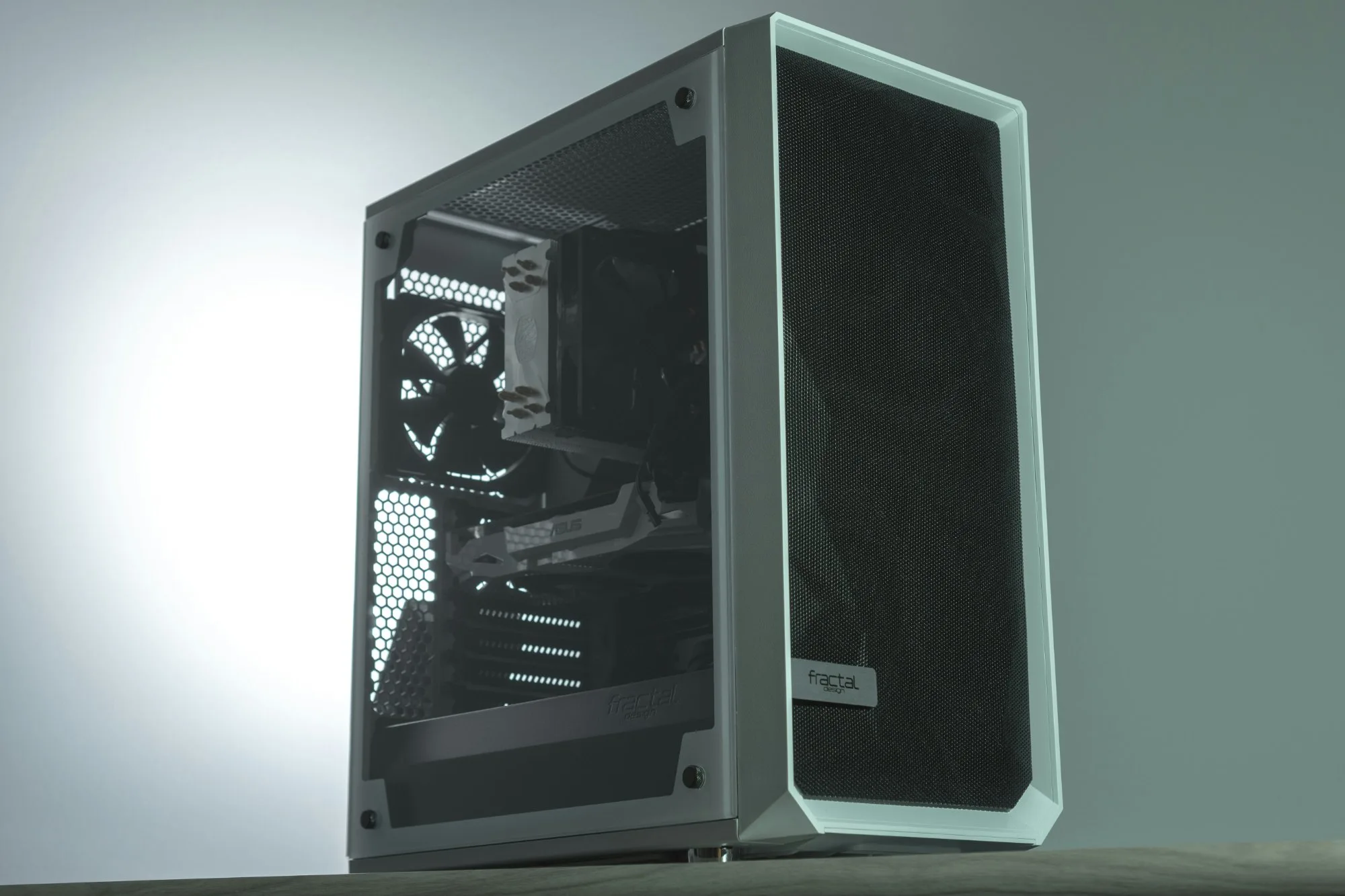 A finished PC tower with a tinted glass side panel, lit against a grey backdrop